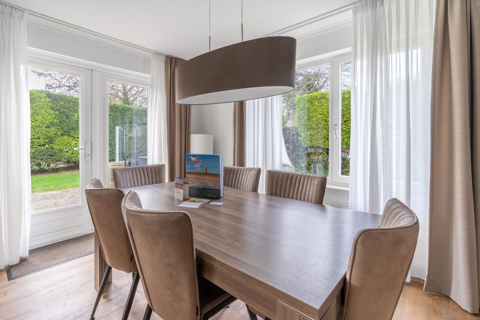 Dining area in Holiday home Honeysuckle 49, De Koog, Texel, overlooking the green garden.