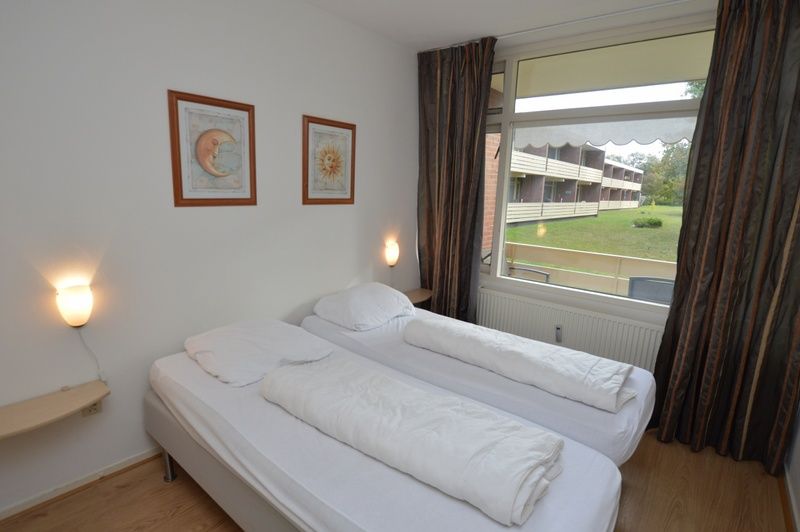 Schlafzimmer im Appartement Kerckeland 110, De Koog Texel, mit bequemen Betten und Gartenblick.