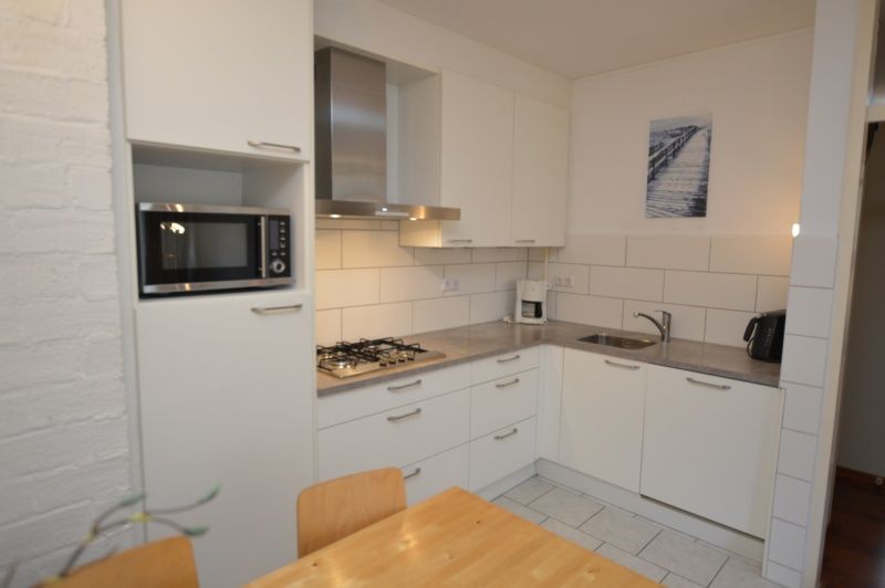 Fully equipped kitchen in Apartment Kerckeland 24, De Koog, Texel with sleek finish and dining table.