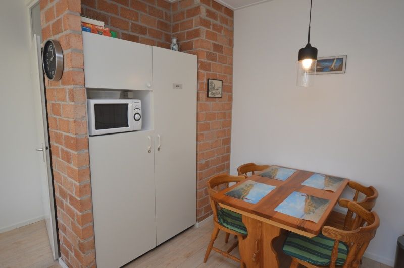 Dining area and kitchen in Apartment Kerckeland 80, De Koog, Texel, Wadden Islands, with wooden table and chairs.