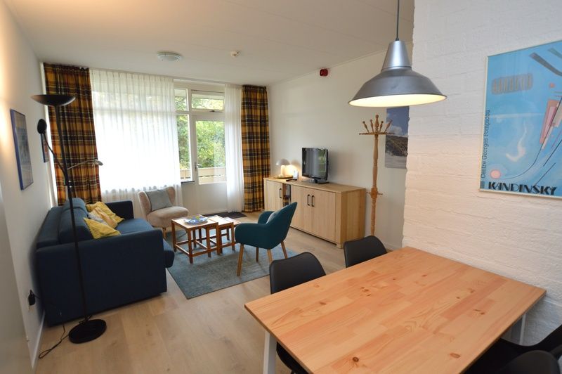 Spacious interior of Apartment Kerckeland 126 in De Koog, Texel, with dining area and view of the greenery.