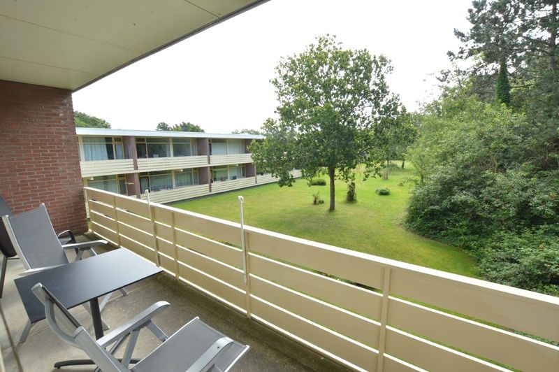 Balcony of Apartment Kerckeland 126, De Koog, Texel, overlooking green surroundings and seating area.