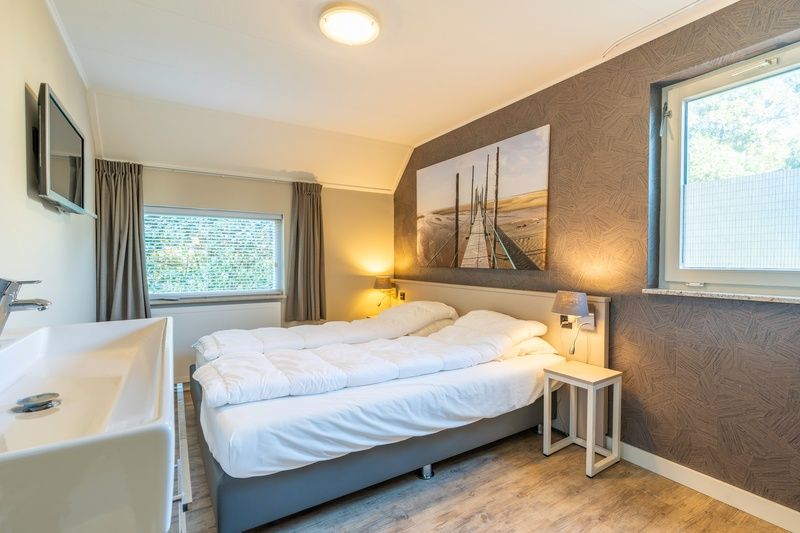 Bedroom with double bed in Holiday Home Honeysuckle 57, De Koog, Texel for a relaxing night's sleep.