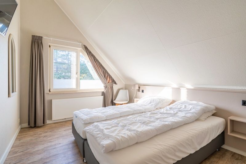 Second bedroom in Holiday home Honeysuckle 57, De Koog, Texel with cozy furnishings and lots of natural light.