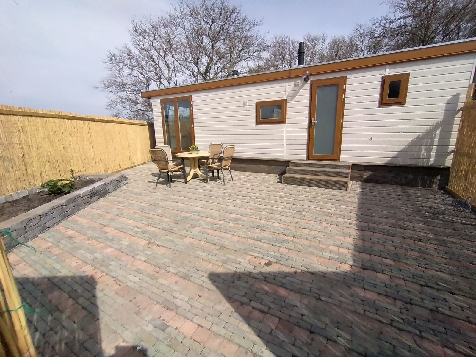 Spacious terrace of Chalet Out and Home in De Koog, Texel, with garden furniture and fence.