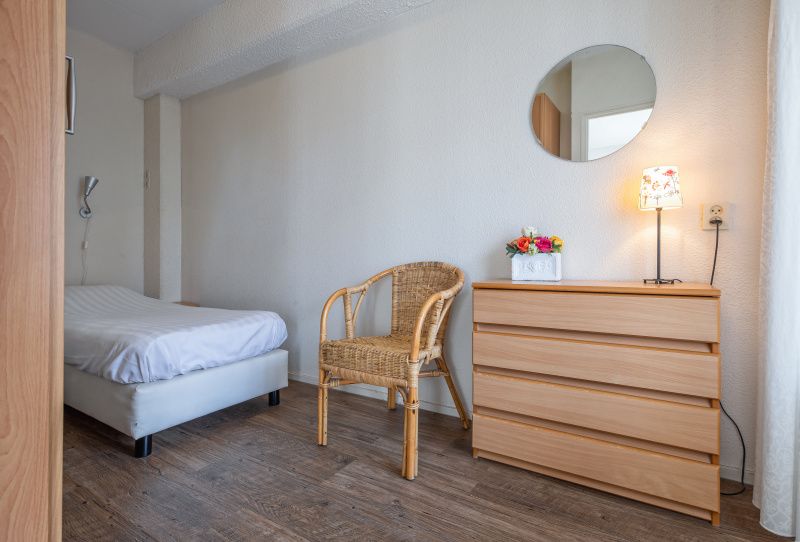 Comfortable bedroom in Motel Texel Apartment with bath (B), De Koog, Texel with single bed and rattan chair.