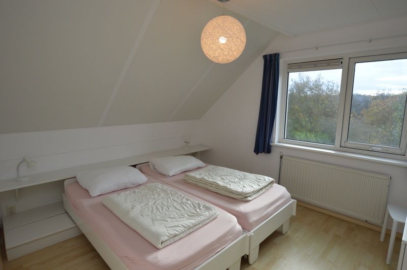 Bright bedroom in Holiday home Stappeland 199, De Koog, Texel, with two single beds and views of the green surroundings.
