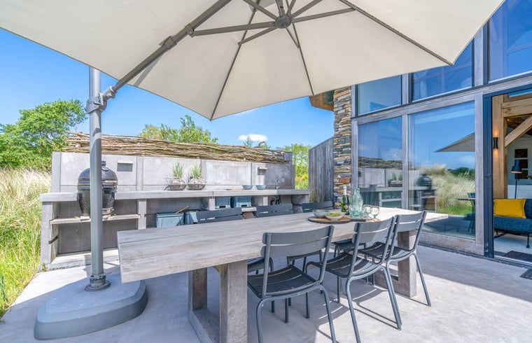 Outdoor terrace with dining table in Holiday home in De Koog, Texel, surrounded by nature.