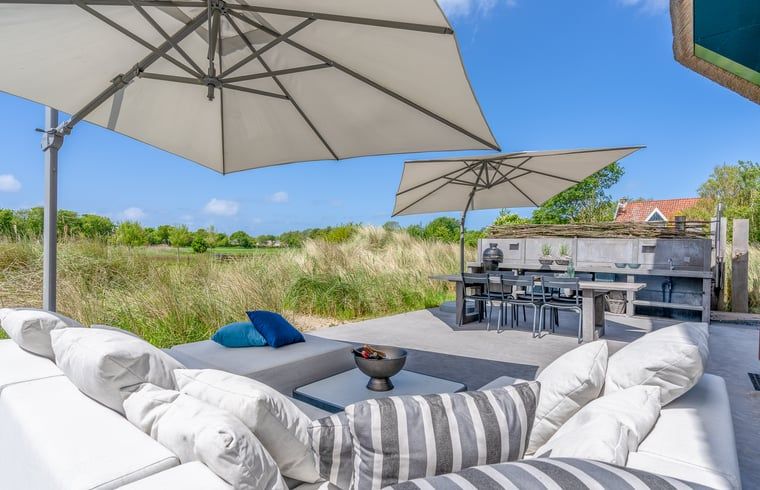 Terrace with parasols in Holiday home in De Koog, Texel, overlooking nature.