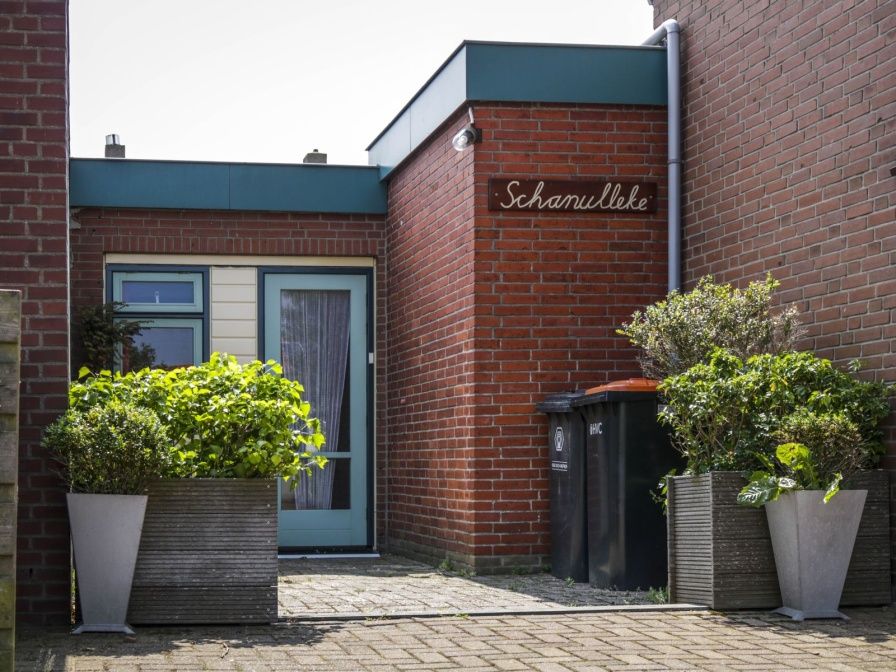 Entrance to vacation home Schanulleke in De Koog, Texel, with green plants and an inviting entrance.