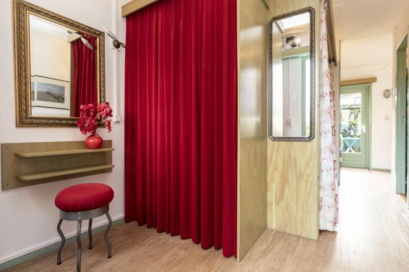 Stylish hall in vacation home Schanulleke, De Koog, Texel, with red curtains and mirror.