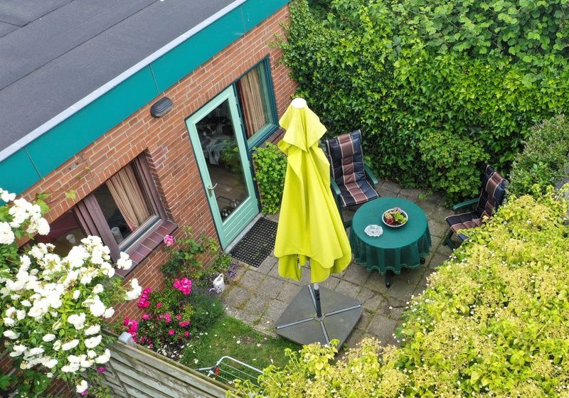 Sunny garden of Schanulleke, De Koog, Texel, vacation home with terrace furniture and green surroundings.