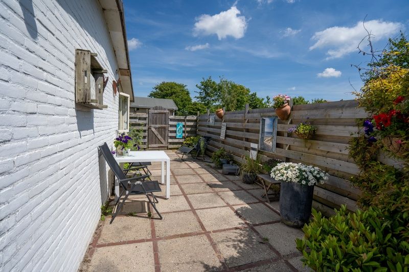 Gemuetliche Terrasse mit Sitzgelegenheiten im Ferienhaus 2490, De Koog, Texel, umgeben von Blumen.