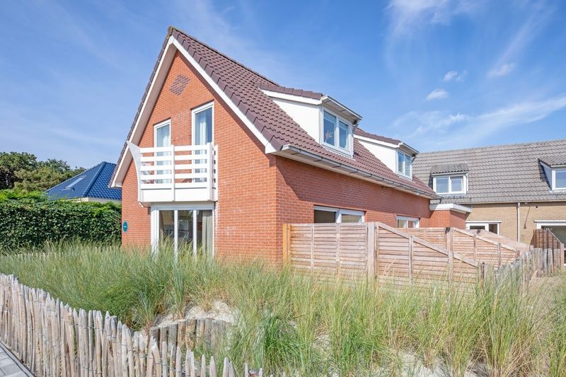 Vogelweelde vacation accommodation in De Koog, Texel with sunny garden and wooden fence.