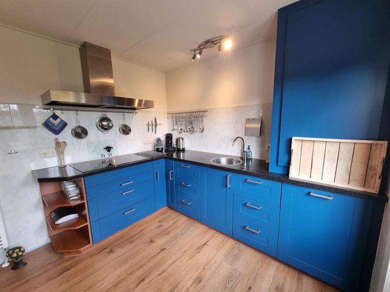 Fully equipped kitchen in Bungalow Epelaan 13, De Koog, Texel, with blue cabinets and modern appliances.