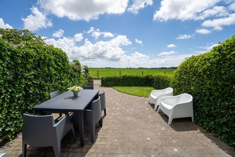 Blick von der Terrasse von Bungalow 1, De Koog, Texel mit gruenen Feldern und freier Luft.
