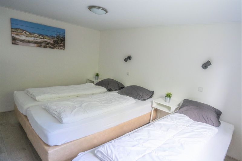 Schlafzimmer im Bungalow 1, De Koog, Texel mit drei bequemen Betten und moderner Einrichtung.