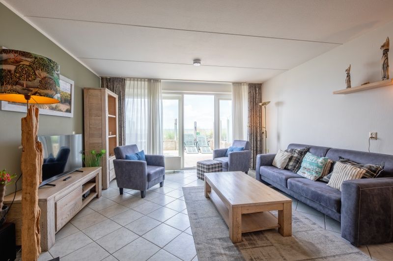 Ruime woonkamer in Appartement - 4-persoons (1533) in De Koog, Texel met comfortabele meubels en toegang tot het terras.