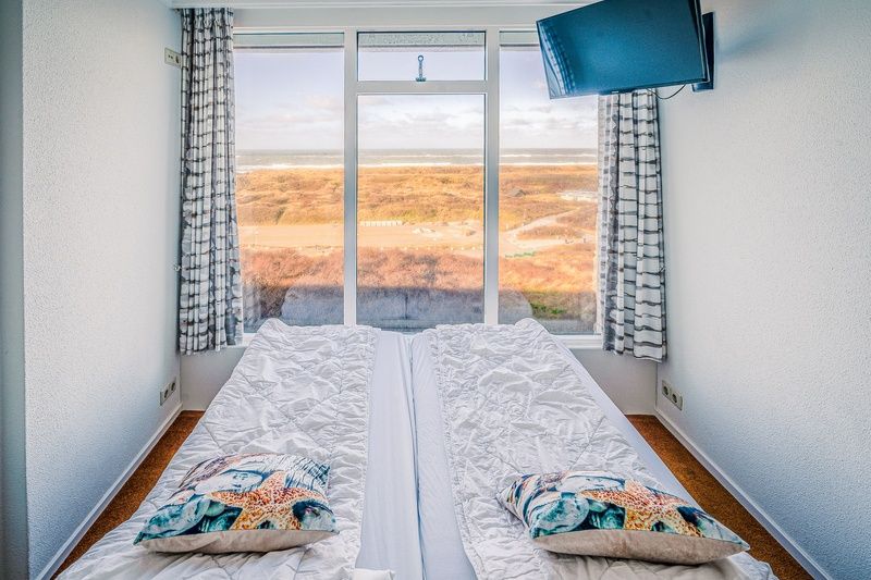 Slaapkamer met panoramisch uitzicht op de duinen in Appartement Juliana 164 Zeezicht, Texel.