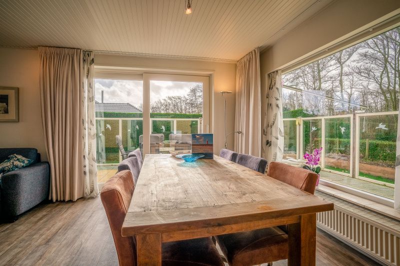 Dining area overlooking garden in Orchismient 2, vacation home De Koog, Texel for cozy meals.