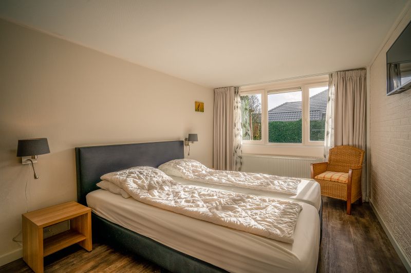 Spacious bedroom with large window in Orchismient 2, vacation home De Koog, Texel for natural light.