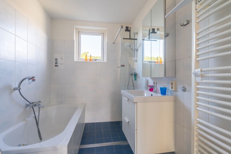 Modern bathroom with bath and shower in Orchismient 2, vacation home De Koog, Texel for ultimate comfort.