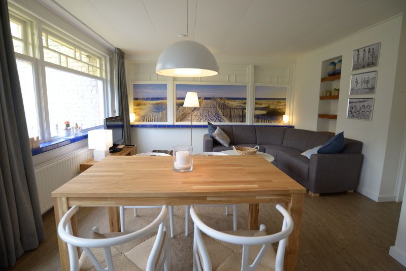 Spacious dining room in Grand Hotel Opduin - Holiday home C, De Koog, Texel, with wooden table and cozy living room.
