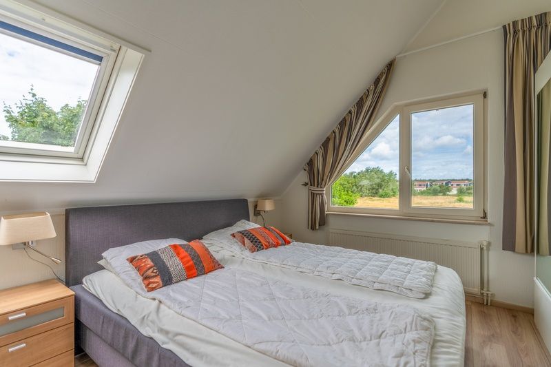 Bedroom with double bed in Holiday home Kamperfoelie 69 with sauna, De Koog, Texel, overlooking the surroundings.