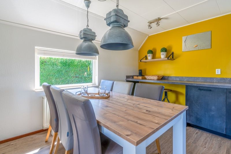 Dining area of Holiday home Honeysuckle 71 in De Koog, Texel with wooden table and modern lamps.