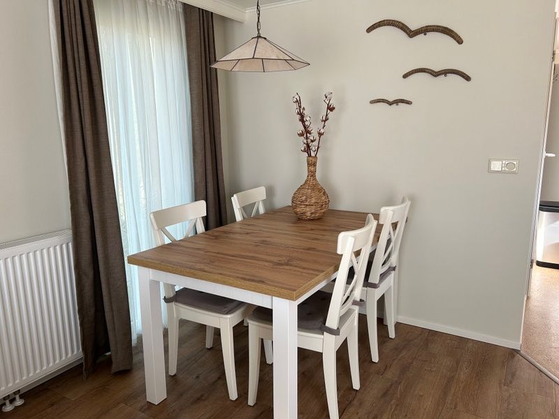 Essecke im Chalet Bregkoog 213 auf Texel, Chaletpark Bregkoog, mit Holztisch und modernen Stuehlen.