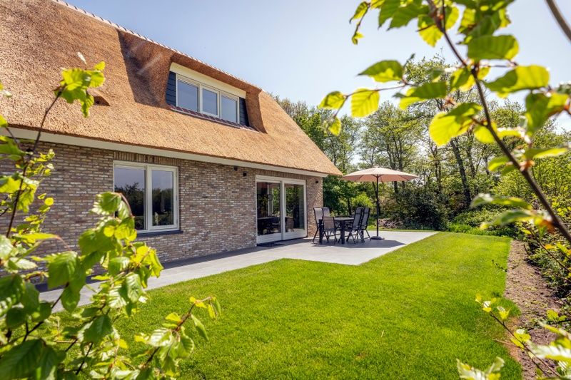 Terrace of Landhuis De Wije Blick, vacation home in De Koog, Texel, with garden furniture and green surroundings.