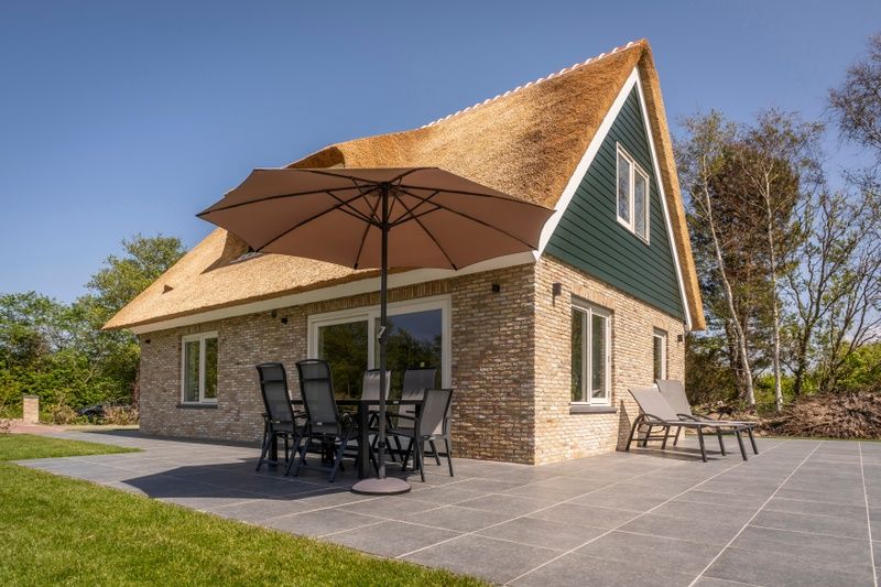 Terrace of Landhuis De Wije Blick in De Koog, Texel, vacation home with parasol and garden furniture.