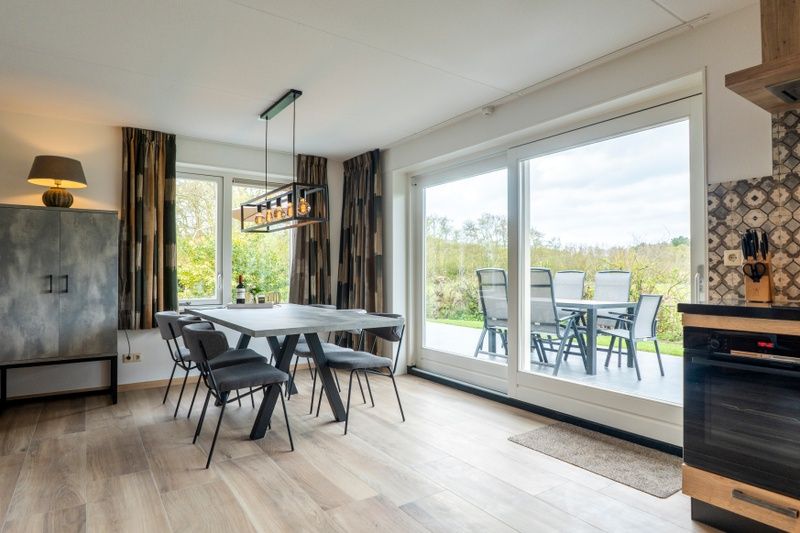 Dining area in Landhuis De Wije Blick, vacation home in De Koog, Texel, overlooking the garden and modern furnishings.