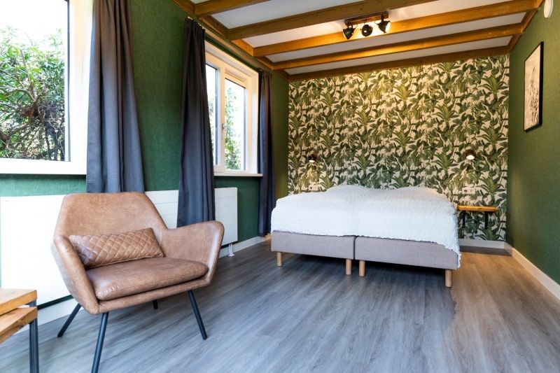 Spacious bedroom in De Koperwiek De Koog Texel with comfortable chair and bed.