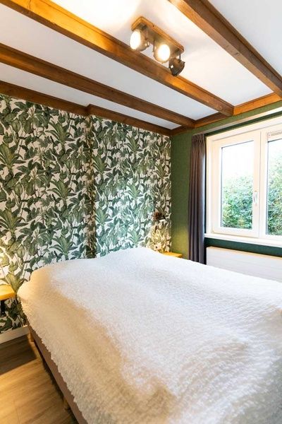 Bedroom of De Koperwiek vacation home De Koog Texel with green wallpaper and wooden beams.