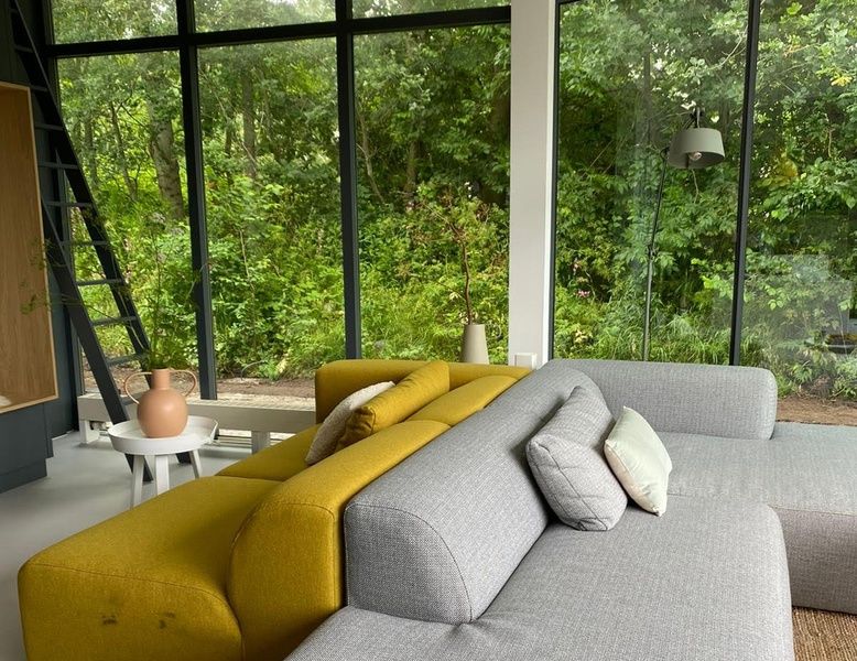 Bright living room in De Koerie vacation home De Koog Texel overlooking lush greenery, perfect for rest.