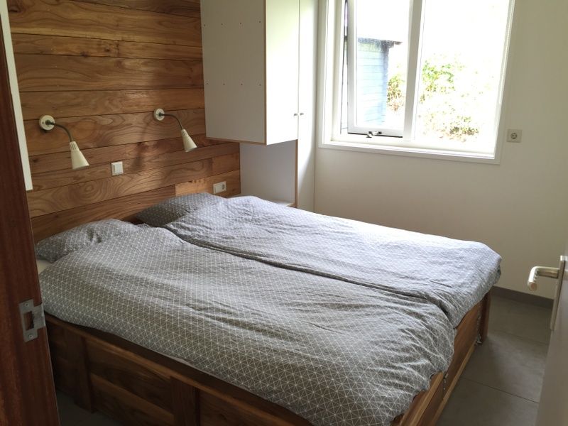 Comfortable bedroom in De Koerie vacation home De Koog Texel with wooden accents and serene look.