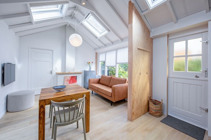 Stilvolles Wohnzimmer des Ferienhauses Pippa auf Texel mit Holzinterieur und grossen Fenstern.