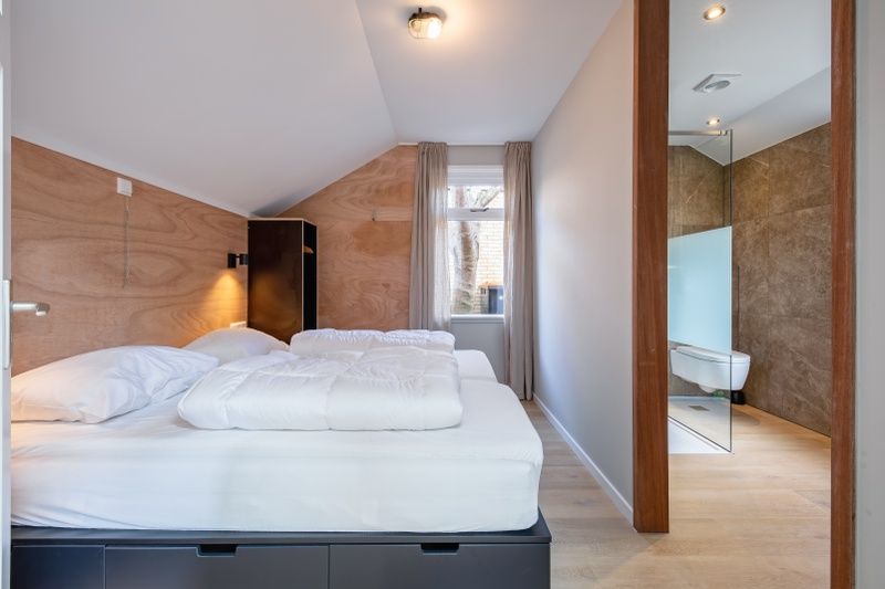 Geraeumiges Schlafzimmer des Ferienhauses Pippa, De Koog, Texel, mit angrenzendem modernen Badezimmer.