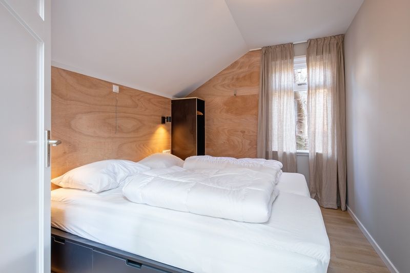 Gemuetliches Schlafzimmer im Ferienhaus Pippa auf Texel mit Holzakzenten und viel Tageslicht.