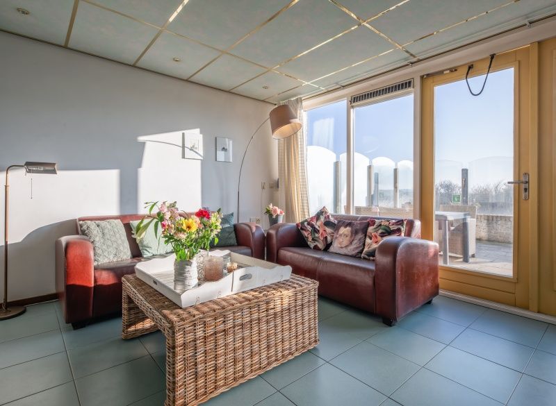 Cozy living room of Resort De Buteriggel - Apartment 9, De Koog, Texel with comfortable sofas and views of nature.