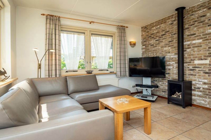 Gemuetliches Wohnzimmer der Villa mit Wintergarten in De Koog, Texel, mit Kamin und gemuetlicher Sitzecke.