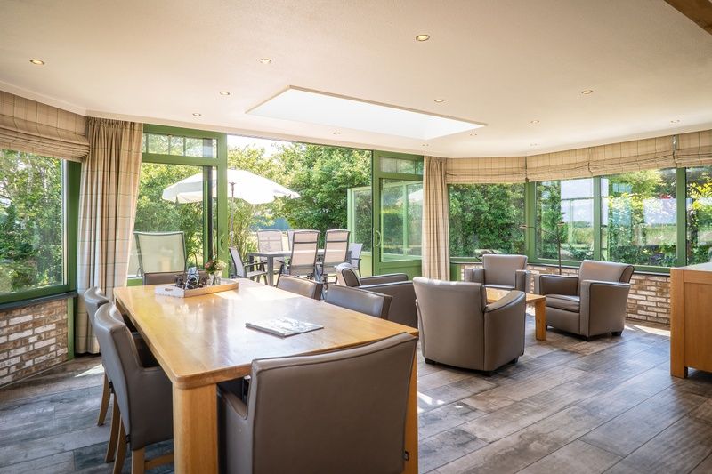 Geraeumiges Esszimmer in der Villa mit Wintergarten, De Koog, Texel, umgeben von Gruen, ideal fuer Urlaubsessen.