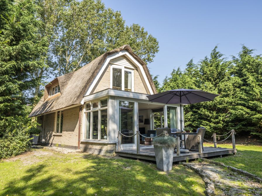 Vacation home Westenwind in De Koog, Texel with thatched roof and terrace among green trees.