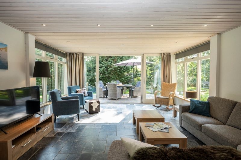 Sunny living room of Westenwind vacation home in De Koog, Texel with large windows and garden view.