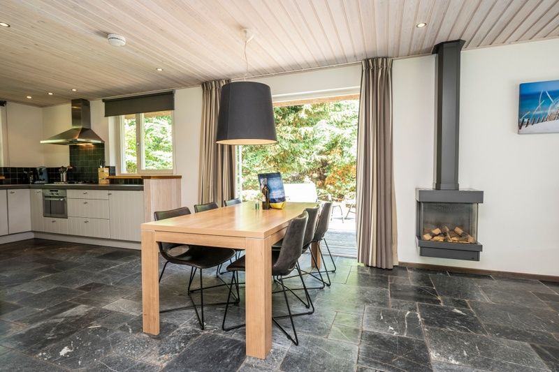 Cozy dining area of Westenwind in De Koog, Texel next to the modern kitchen and fireplace.