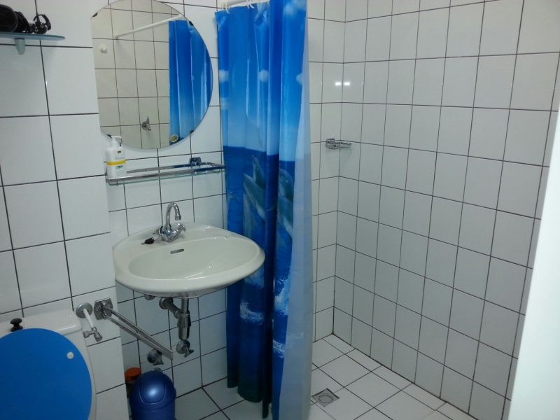 't Kerckeland - Apartment Kerckeland 86, De Koog, Texel: modern bathroom with shower and sink, with fresh blue accents.