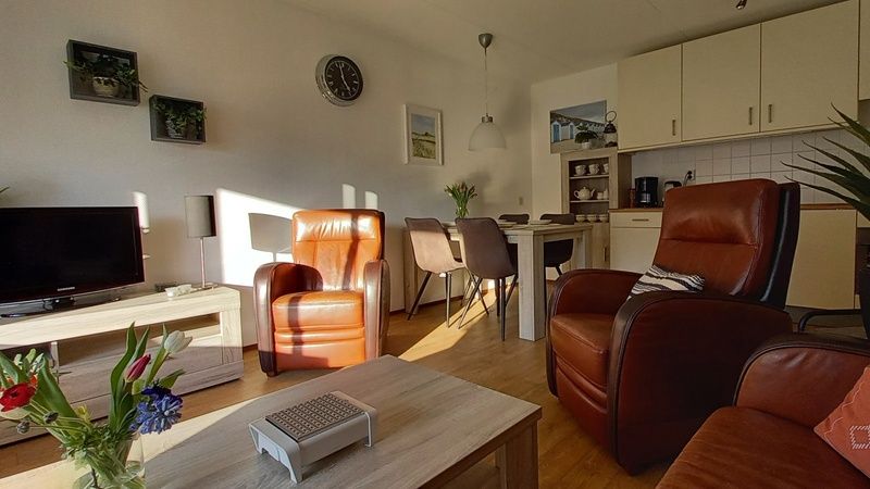 Offene Kueche und Essbereich in De Pelikaan Apartments, De Koog, Texel mit bequemen Stuehlen und Tisch.