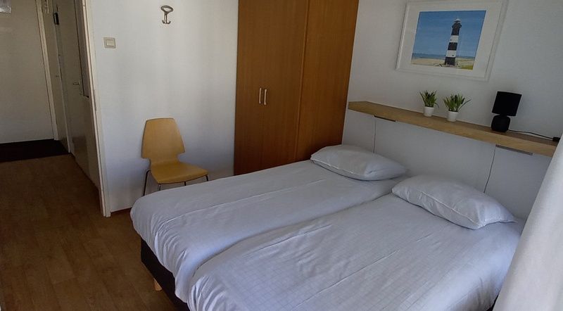 Komfortables Schlafzimmer in De Pelikaan Apartments, De Koog, Texel mit zwei Betten und ruhiger Einrichtung.