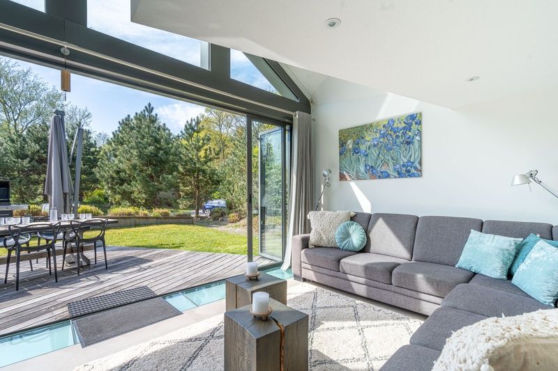 Spacious living room in Duynzoom Villa 5, a vacation home in De Koog, Texel, with large windows and garden views.